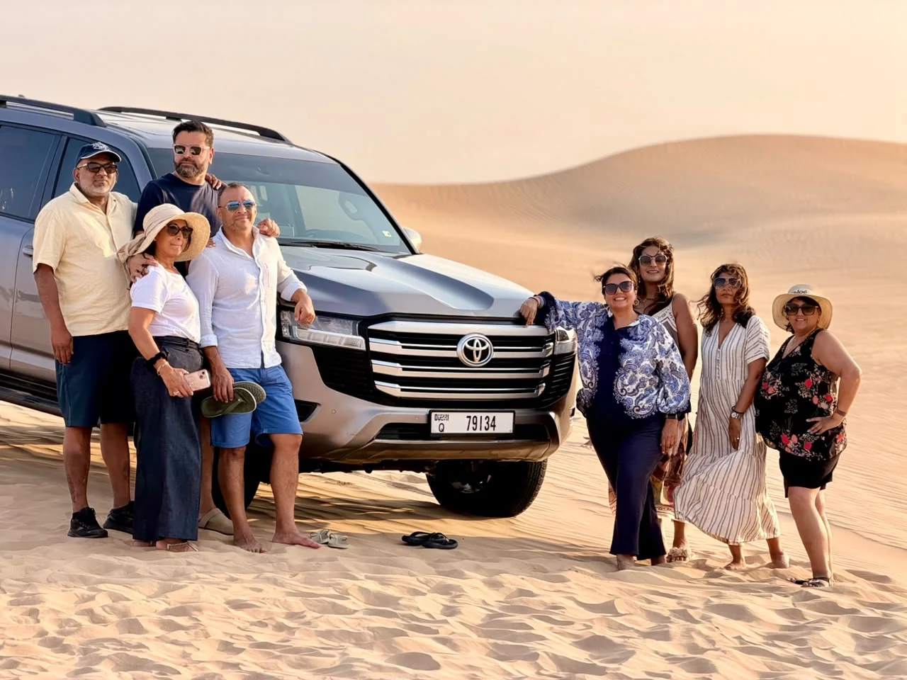 Private desert safari guests beside a Toyota Land Cruiser in Abu Dhabi dunes